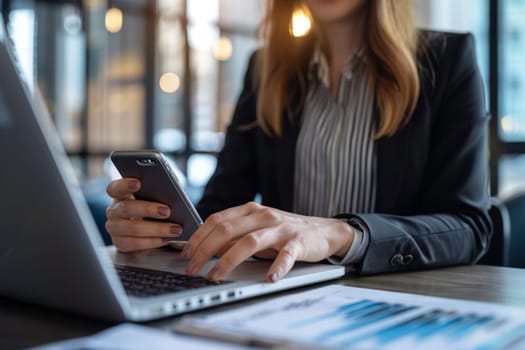 Close up of Businesswoman using smartphone while working on laptop.