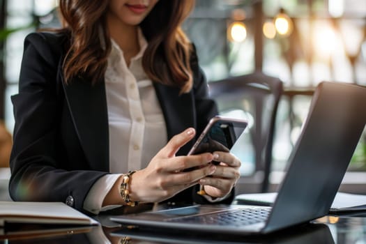 Close up of Businesswoman using smartphone while working on laptop.