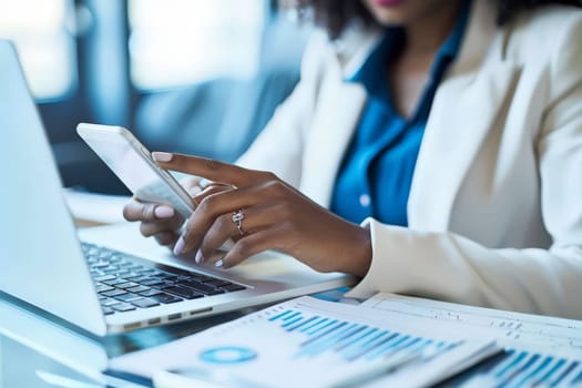 Close up of Businesswoman using smartphone while working on laptop.