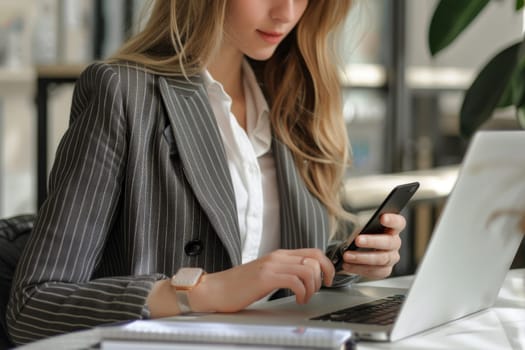 Close up of Businesswoman using smartphone while working on laptop.