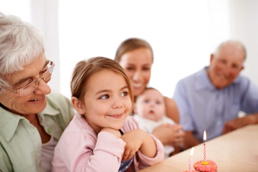 Family, birthday party and cupcake with candle for celebration, mother and grandparents with children at home. Happy young girl with cake, people and smile for anniversary with dessert at event.