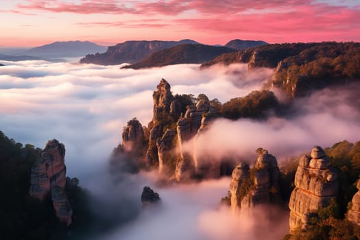 High rocks in pink clouds and fog. Beautiful landscape of mountain peaks.