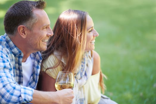Couple, picnic and wine glasses for bonding in outdoor nature, love and romance in relationship on weekend. Alcohol, conversation and people in countryside, adventure and grass or happy on vacation.