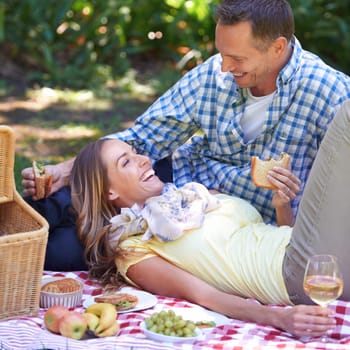 Couple, picnic and food for bonding in outdoor nature, love and romance in relationship on weekend. Alcohol, conversation and people on date in countryside, adventure and laugh for joke on vacation.