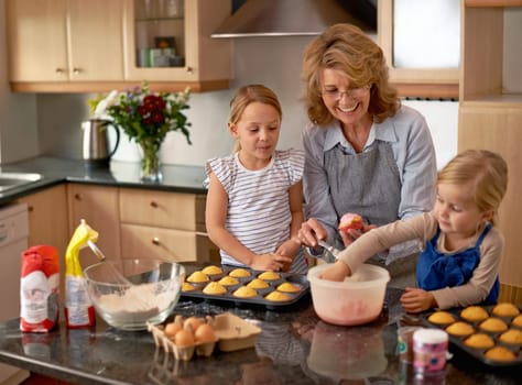 Grandmother, children and baking cupcakes or teaching with icing decorations or learning creativity, bonding or teamwork. Woman, siblings and sweet treats or helping with ingredients, snack or recipe.