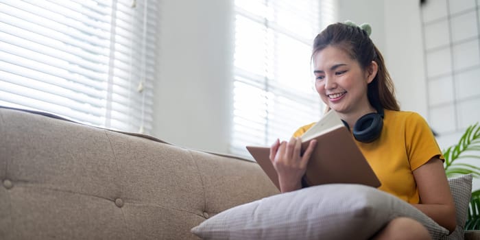 Young pretty woman siting on sofa and reading a book enjoys of rest. relaxing at home.