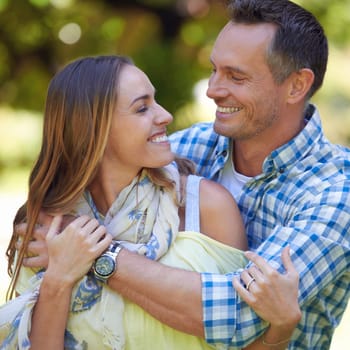 Couple, happy and hug in park with smile for adventure, bonding and anniversary in countryside. Nature, man and woman with love in forest on date, holiday and vacation together for commitment.