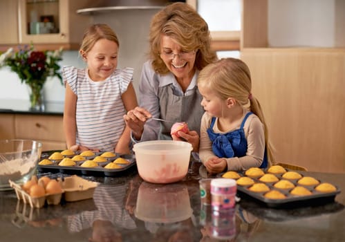 Grandma, children and smile for teaching, baking and decorating for family, play and bonding at home. Happy, pensioner and girl with cupcake, laugh and icing for creative fun together in kitchen.