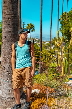 Portrait of stylish student in California with palm trees in the background during a sunny colorful day. High quality photo