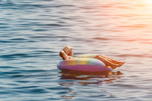 Summer Vacation Woman in hat floats on an inflatable donut mattress, a water toy swim ring. Unrecognizable young woman relaxing and enjoying family summer travel holidays vacation on the sea