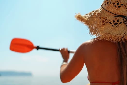 Woman in kayak back view. Happy woman with long hair in a swimsuit and hat floating in kayak on the sea. Summer holiday vacation. Summer holidays vacation at sea