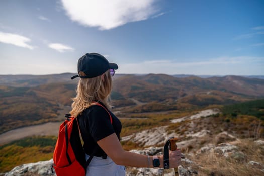 woman on mountain peak looking in beautiful mountain valley in autumn. Landscape with sporty young woman, blu sky in fall. Hiking. Nature.