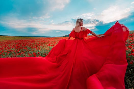 Woman poppy field red dress. Happy woman in a long red dress in a beautiful large poppy field. Blond stands with her back posing on a large field of red poppie