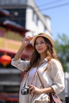 Portrait of smiling young woman walking at Chinatown street market in Thailand.