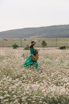 Happy woman in a field of daisies with a wreath of wildflowers on her head. woman in a green dress in a field of white flowers. Charming woman with a bouquet of daisies, tender summer photo.