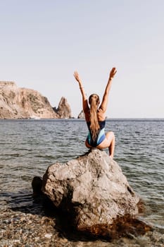 Woman beach vacation photo. A happy tourist in a blue bikini enjoying the scenic view of the sea and volcanic mountains while taking pictures to capture the memories of her travel adventure