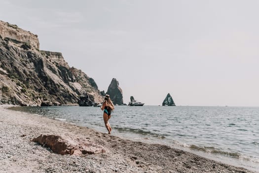 Woman beach vacation photo. A happy tourist in a blue bikini enjoying the scenic view of the sea and volcanic mountains while taking pictures to capture the memories of her travel adventure