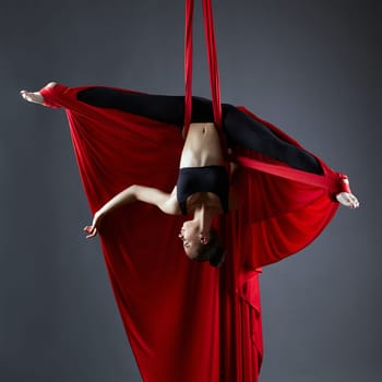 Image of graceful dancer on aerial silks posing upside down