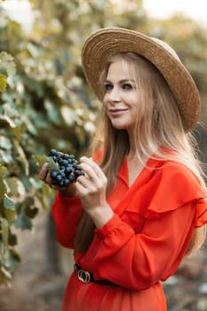 portrait of a happy woman in the summer vineyards at sunset. woman in a hat and smiling