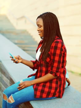 Happy young smiling african woman with smartphone student in the city