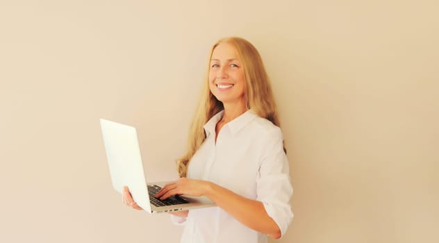 Happy caucasian middle-aged woman working with laptop at home