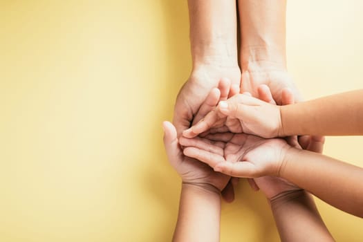 A touching gesture captured in a studio top view shot, family hands stacked on an isolated background. Parents and children hold an empty space reflecting support and love.