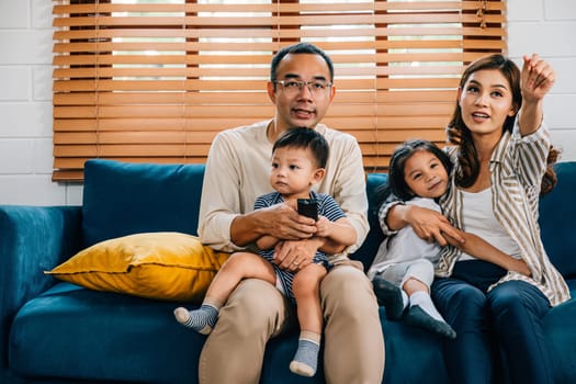 In the cozy living room a cheerful family with kids bonds over TV movies. The father mother son and daughter radiate joy and togetherness during their relaxation time.