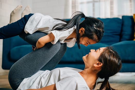 A mother and her child share a delightful family fitness moment playfully 'flying' like airplanes during their Pilates and yoga routine fostering trust harmony and happiness.