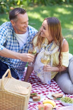 Couple, picnic and wine on date in outdoor nature, love and romance in relationship on weekend. Alcohol, conversation and people to relax in countryside, adventure and grass for care on vacation.