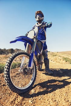 Motorcycle, sports and danger with biker person outdoor, low angle with uniform for riding on dirt track. Speed, power and risk with motorbike, transportation and adventure for adrenaline and travel.