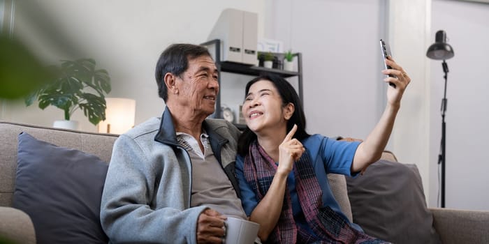 Happy old couple elderly taking selfie on cellphone, senior mature spouses wife and husband laughing holding phone make self portrait on smartphone camera.