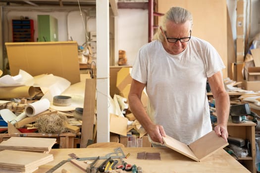 Carpenter artist working on wood craft at workspace producing wooden furniture with professional tools for crafting. High quality photo