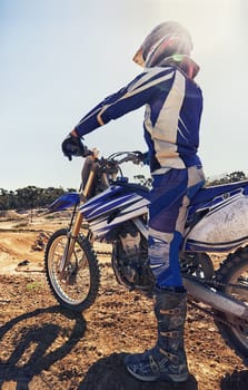 Motorcycle, extreme sports and danger with biker person outdoor, sunshine with uniform for riding on dirt track. Speed, power and risk with motorbike, transportation and adventure for adrenaline.