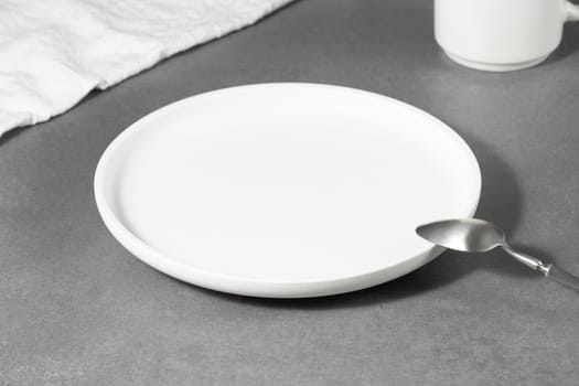Empty white plate over gray concrete background.