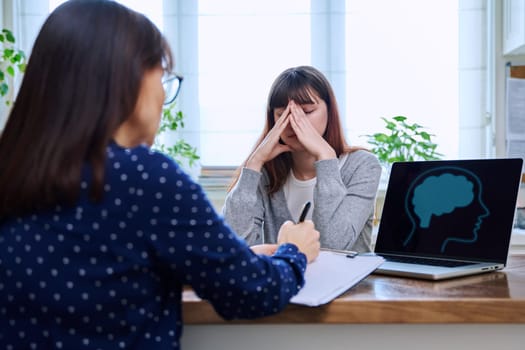 Sad, serious teenage girl at a session in the office of a mental professional, psychologist, counselor, social worker. Feelings, difficulties, problems, depression, stress, youth concept