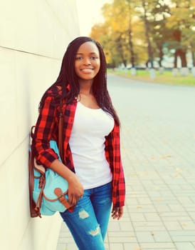 Portrait of young african woman with backpack on the city street