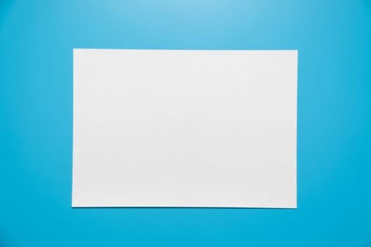 Empty white paper sheet isolated on blue background..