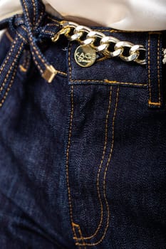 Chic dark blue jeans with a trendy gold chain belt. High-waisted, slim fit design for a touch of luxury and style.