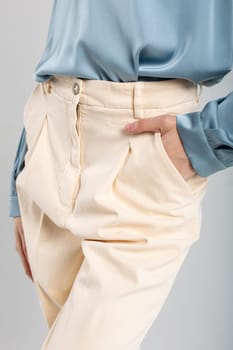 Fashion model in beige pants and blue blouse with hand in pocket on isolated background. Suitable for fashion ads.