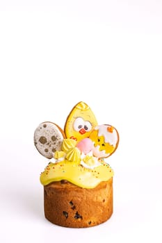 A small, round, traditional Easter cake with yellow icing and a chick decoration made of icing on top. Isolated on a white background.