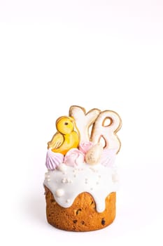 A small traditional Easter cake with yellow icing and a cute chick decoration on top, isolated on a white background.