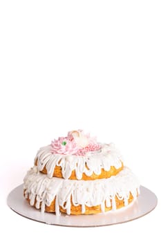 Two-tiered white cake with pink flowers and pearls on white plate isolated on background. Elegant and beautiful dessert.