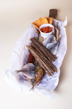 The smoked fish includes salmon, trout, and whitefish. The fish is served on a wooden board with a bowl of red pepper flakes.