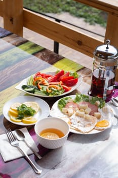 Delicious breakfast of eggs, cheese, bacon, and tomatoes served on outdoor cafe table near lake shore. Enjoy your meal al fresco