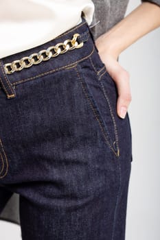 Chic dark blue jeans with a trendy gold chain belt. High-waisted, slim fit design for a touch of luxury and style.