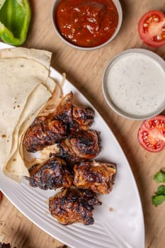 liver kebab with pita bread on a white plate with vegetables and herbs.