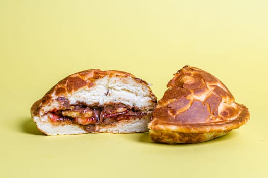 a closed cut burger with juicy filling on a yellow background.