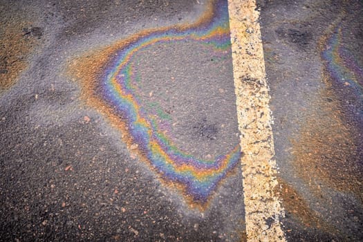 Oil, gasoline, or oil spill on wet asphalt with a parking lot and a dividing line