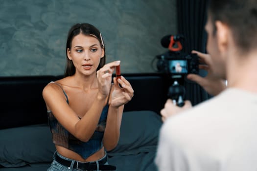 Man filming video on young woman making beauty and cosmetic tutorial video content for social media. Beauty blogger smiles to camera while showing how to beauty care to audience or follower. Unveiling