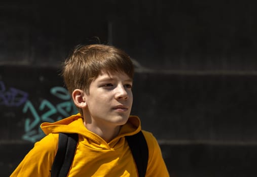 Urban teen or gen z portrait on the street. Dreamy boy in yellow hoodie.